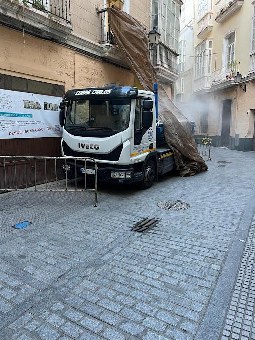 Camión descargando escombros cubierto con lona en plena obra urbana